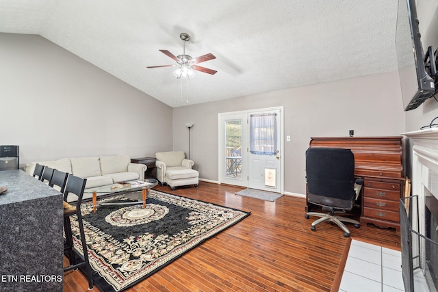 home office with ceiling fan, vaulted ceiling, hardwood / wood-style floors, and a textured ceiling