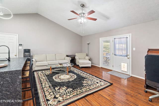 living room featuring vaulted ceiling, hardwood / wood-style floors, sink, ceiling fan, and a textured ceiling