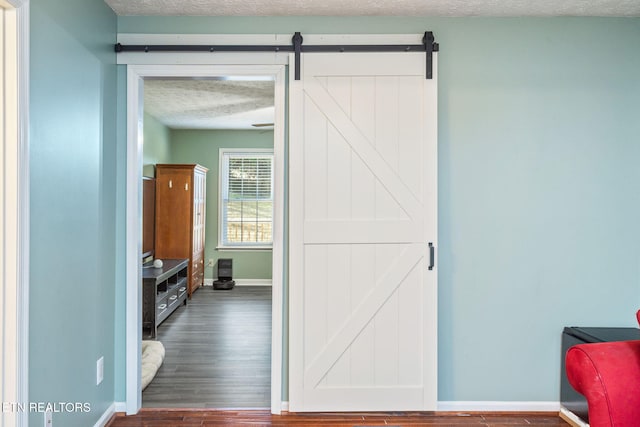 interior space with a barn door, dark hardwood / wood-style floors, and a textured ceiling