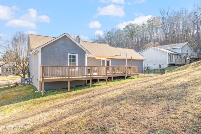 rear view of house featuring a wooden deck and a lawn