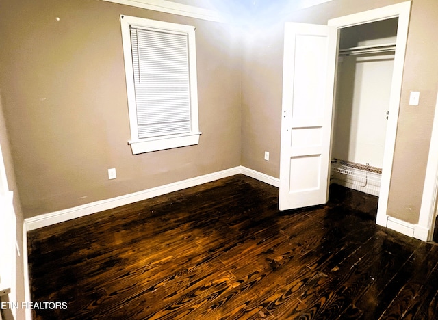 unfurnished bedroom with dark wood-type flooring and a closet