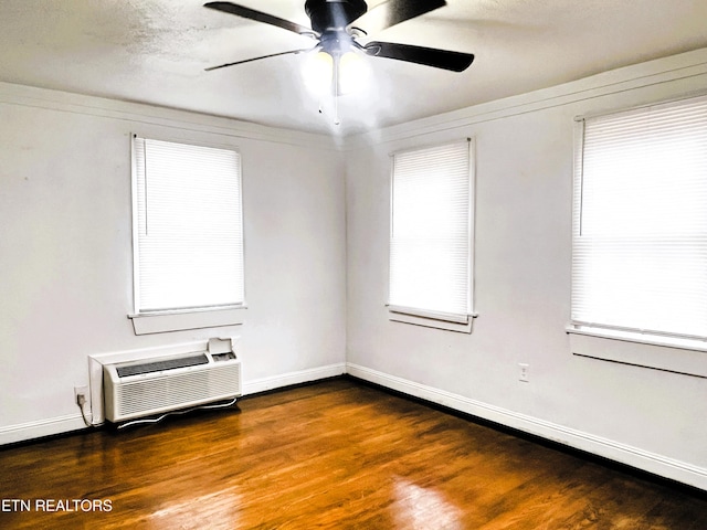 unfurnished room featuring an AC wall unit, dark wood-type flooring, and ceiling fan