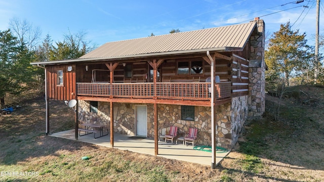 back of property with a chimney, a patio area, metal roof, log exterior, and stone siding