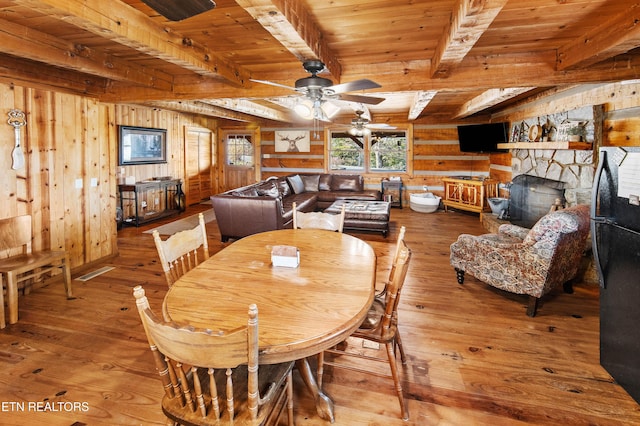 dining room featuring beam ceiling, wood walls, wood finished floors, and wood ceiling