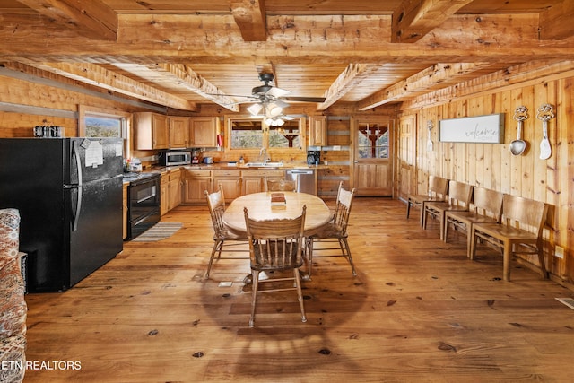 dining room with ceiling fan, beamed ceiling, light wood-style flooring, and wooden walls