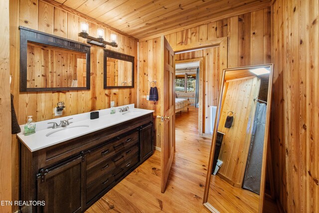 bathroom with double vanity, wood finished floors, a sink, and wood ceiling