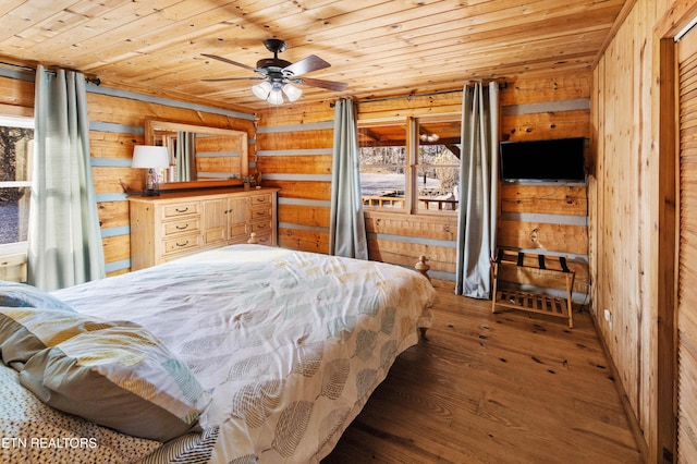 bedroom with dark wood-style floors, wooden ceiling, and wood walls