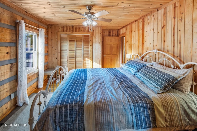 bedroom featuring wood walls, wood ceiling, ceiling fan, and a closet