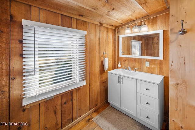 bathroom with wood walls, wooden ceiling, wood finished floors, and vanity