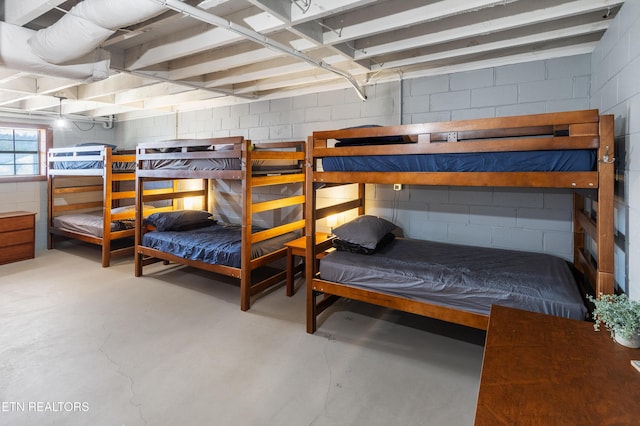 bedroom featuring concrete block wall and concrete floors