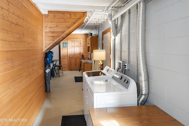 laundry room with washing machine and dryer, laundry area, wood walls, and concrete block wall