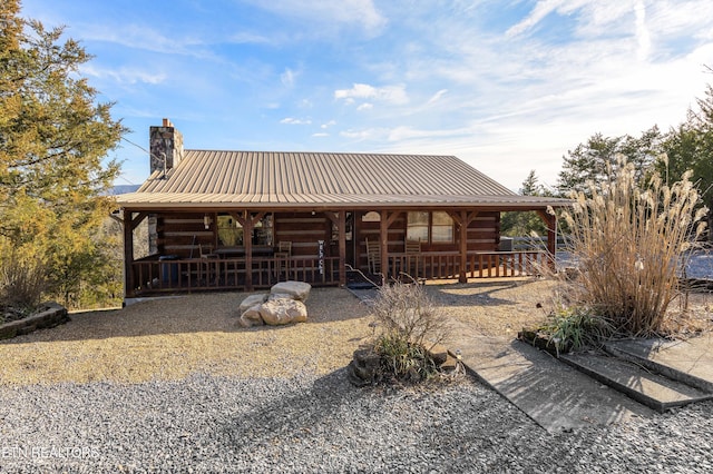 view of front of house featuring a chimney, metal roof, and log exterior