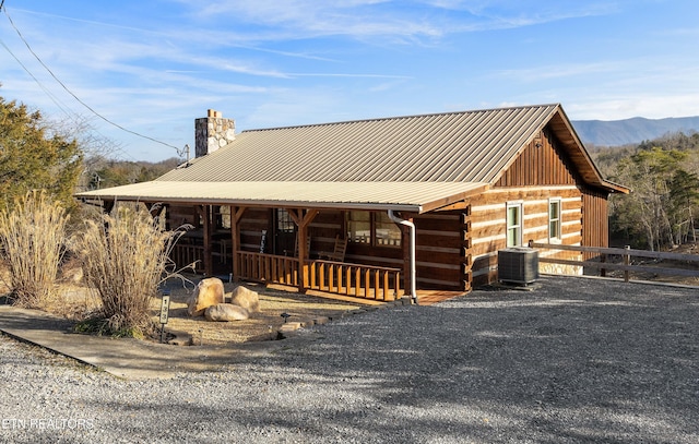 cabin featuring a chimney, metal roof, a mountain view, log siding, and cooling unit