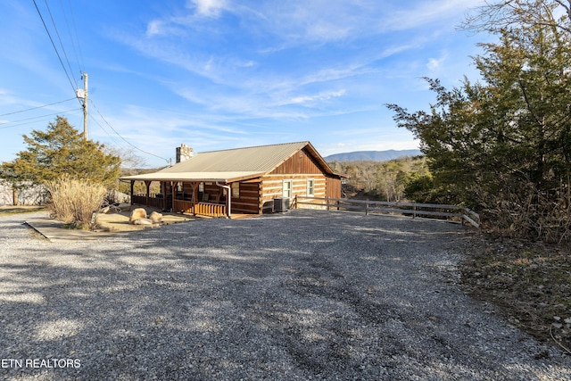 view of front facade with metal roof, central AC, log exterior, and a mountain view