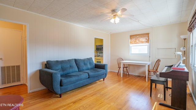 living room featuring ornamental molding, ceiling fan, and light hardwood / wood-style flooring