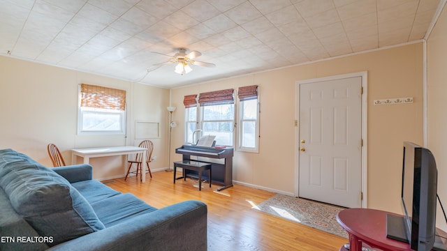 living room with ornamental molding, ceiling fan, and light hardwood / wood-style flooring