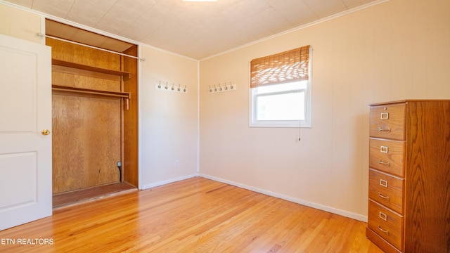 unfurnished bedroom featuring crown molding, light hardwood / wood-style floors, and a closet