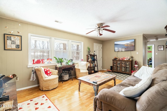 living room with ceiling fan, a textured ceiling, and light hardwood / wood-style floors