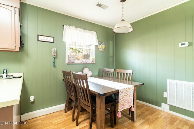 dining room with crown molding and light hardwood / wood-style floors