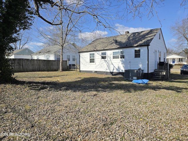 rear view of property with cooling unit and a lawn