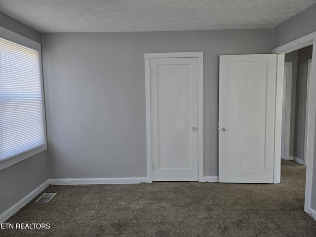 unfurnished bedroom with dark carpet and a textured ceiling