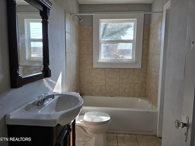 full bathroom featuring vanity, a healthy amount of sunlight, tiled shower / bath, and toilet