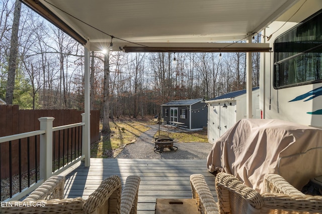 wooden deck with a shed and an outdoor fire pit