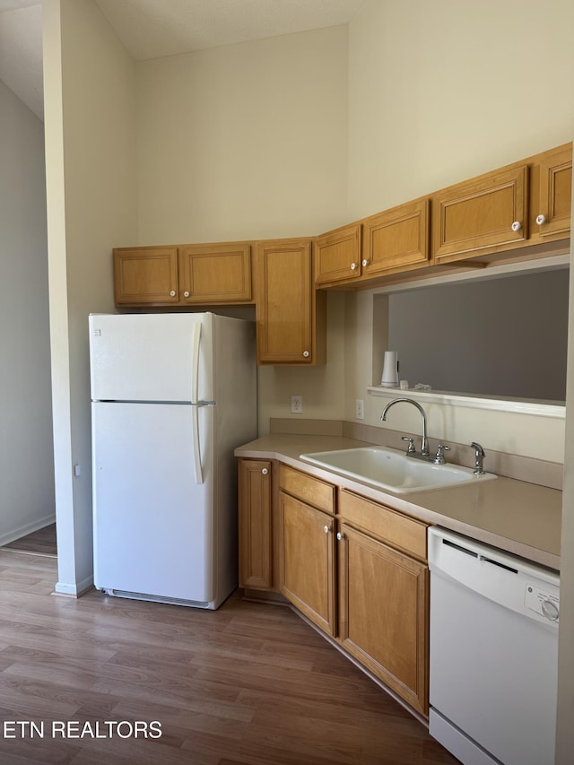 kitchen with light hardwood / wood-style floors, sink, white appliances, and a towering ceiling