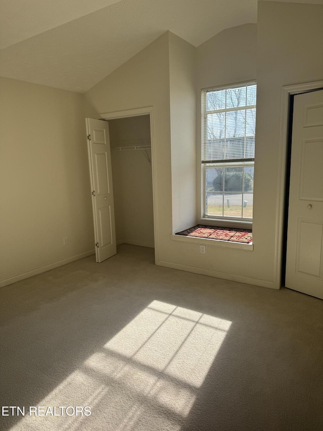 unfurnished bedroom featuring lofted ceiling, a closet, and carpet flooring