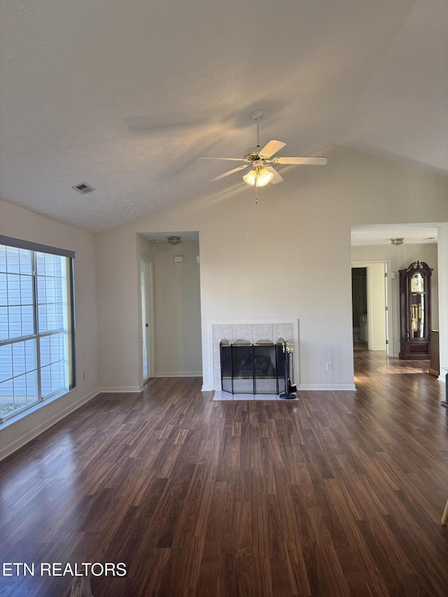 unfurnished living room featuring ceiling fan, lofted ceiling, dark hardwood / wood-style floors, and a tiled fireplace