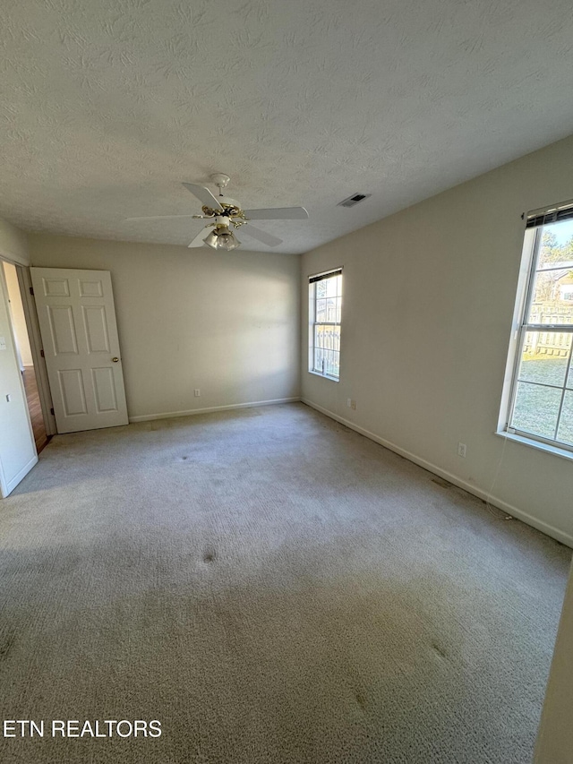 carpeted spare room featuring ceiling fan and a textured ceiling