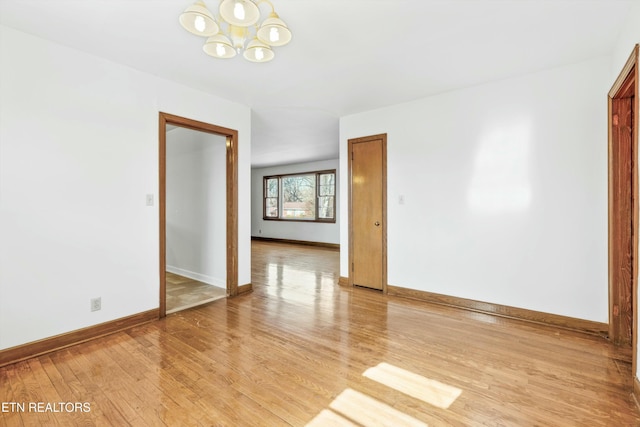 unfurnished room with a notable chandelier and light wood-type flooring