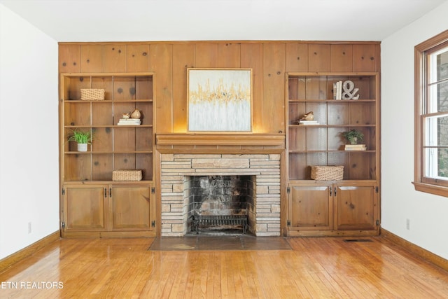 unfurnished living room featuring a fireplace, light hardwood / wood-style floors, and a wealth of natural light