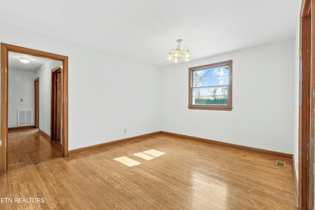 unfurnished room with a chandelier and hardwood / wood-style floors