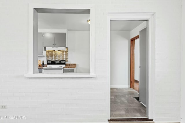 kitchen featuring brick wall and electric range