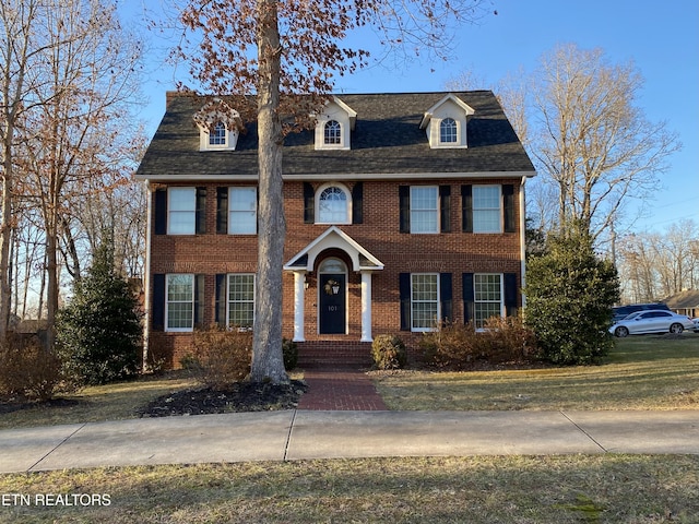 colonial-style house with brick siding and roof with shingles