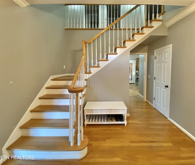 staircase with hardwood / wood-style flooring and a high ceiling