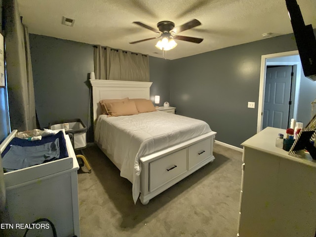 bedroom featuring ceiling fan, light carpet, and a textured ceiling