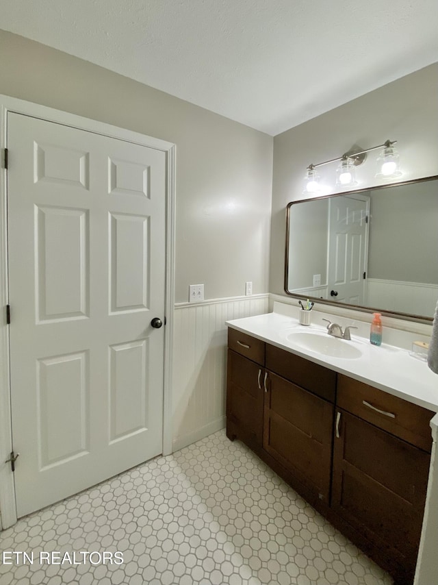 bathroom with a wainscoted wall, tile patterned floors, and vanity