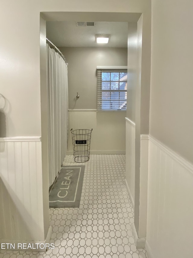 full bath featuring curtained shower, wainscoting, and visible vents