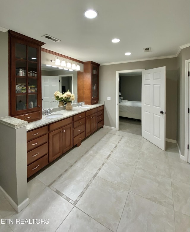 ensuite bathroom featuring crown molding, visible vents, and a sink