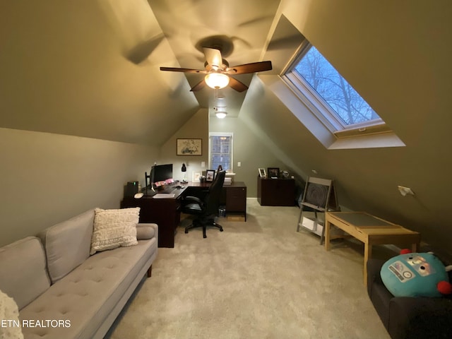 office space featuring ceiling fan, vaulted ceiling with skylight, and light carpet