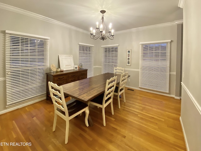 dining room featuring hardwood / wood-style flooring, ornamental molding, and a notable chandelier