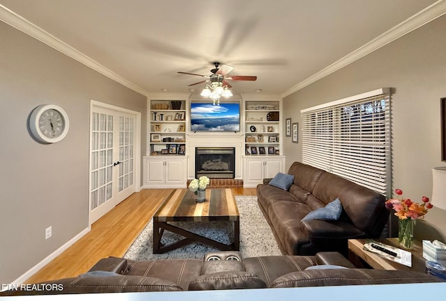 living room featuring ceiling fan, light hardwood / wood-style floors, crown molding, built in shelves, and french doors