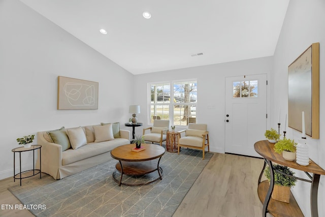 living room featuring lofted ceiling and light hardwood / wood-style floors