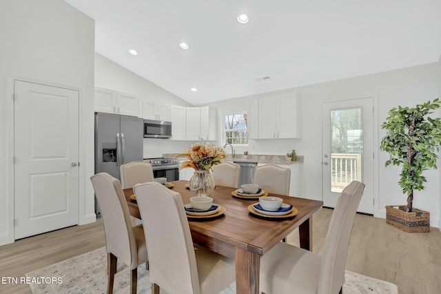 dining space with sink, vaulted ceiling, and light wood-type flooring