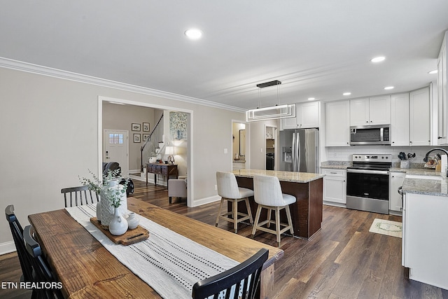 kitchen featuring stainless steel appliances, white cabinets, light stone counters, and decorative light fixtures