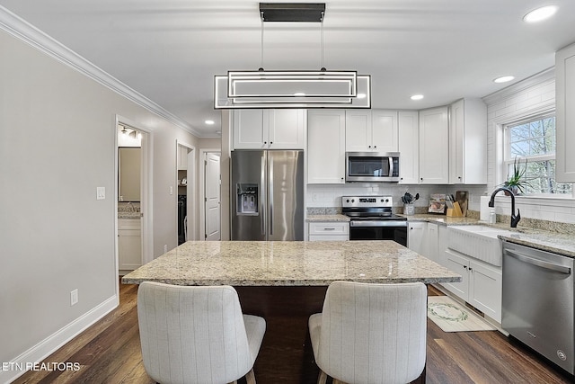 kitchen featuring pendant lighting, light stone counters, a kitchen island, and appliances with stainless steel finishes