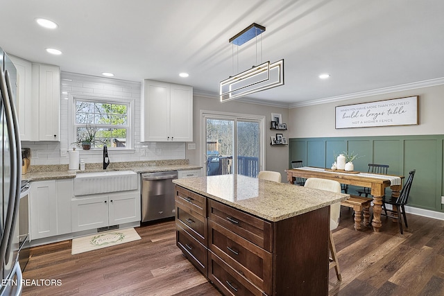 kitchen with sink, appliances with stainless steel finishes, white cabinetry, hanging light fixtures, and a center island