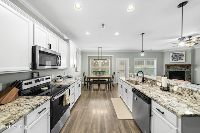 kitchen with pendant lighting, white cabinetry, ornamental molding, and appliances with stainless steel finishes